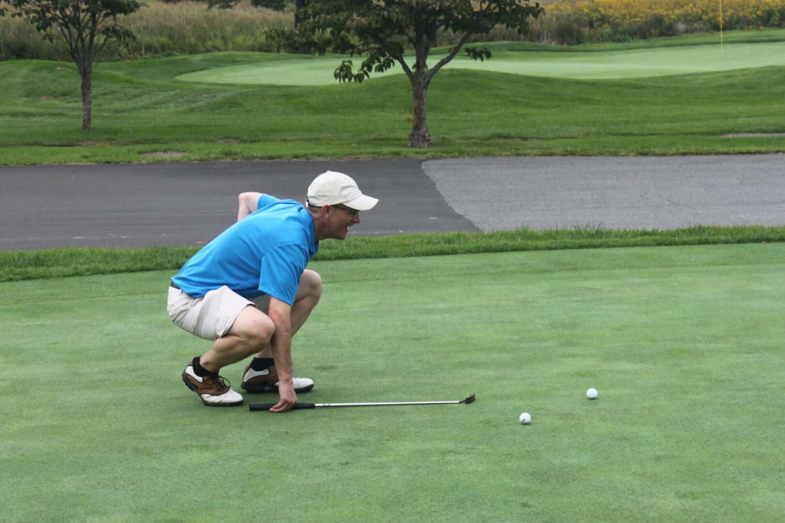 A man crouching down on a golf course.