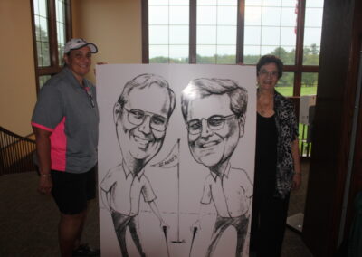 Two people standing next to a caricature.