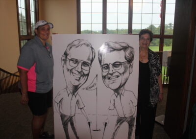 Two people standing next to a caricature.