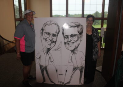 Two people standing next to a caricature.