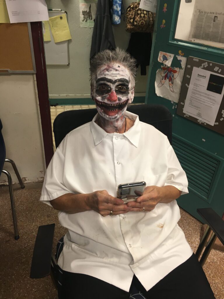 A person with face paint sitting on a chair