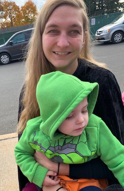 A woman carrying a kid with green jacket