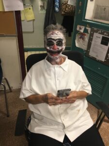 A woman dressed as a clown sitting in a chair.
