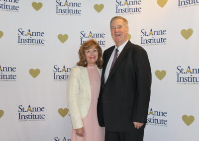 A man and woman standing in front of a heart banner.