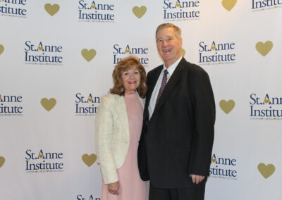 A man and woman standing in front of a heart banner.