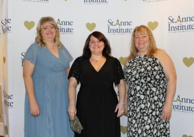 Three women standing in front of a heart banner.