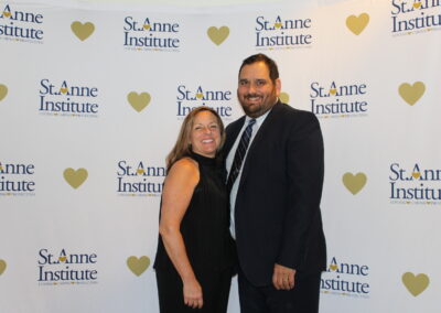 A man and woman posing in front of a heart banner.