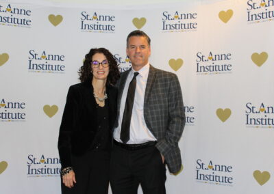 A man and woman standing in front of a heart banner.