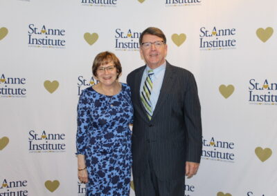 A man and woman standing in front of a heart banner.