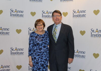 A man and woman standing in front of a heart banner.