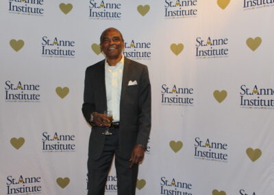 A man in a suit standing in front of a heart shaped wall.