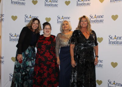 Four women posing for a photo at a red carpet event.