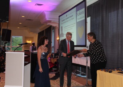 A woman is handing over an award to a man.